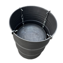 Lade das Bild in den Galerie-Viewer, Eine schwarze Metalltonne mit Ketten, der als Feuerfass mit Feuerkorb dient, steht auf einem Untergrund.