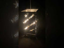 Laden und Abspielen von Videos im Galerie-Viewer, Brennende Metallkiste mit kunstvollen Mustern, platziert in einem schönen Garten während der Urlaubszeit.